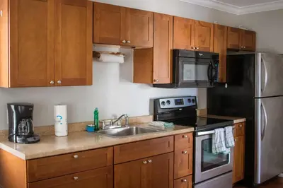 a kitchen with wooden cabinets and a stainless steel refrigerator at Riptide Oceanfront Hotel in Hollywood