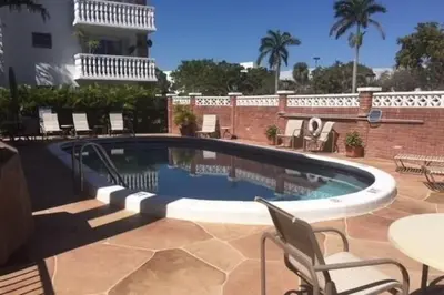a swimming pool with chairs and tables on a patio at Large Lush Oasis Paradise by FLL Beach and Galleria - 2bd 2ba in Fort Lauderdale