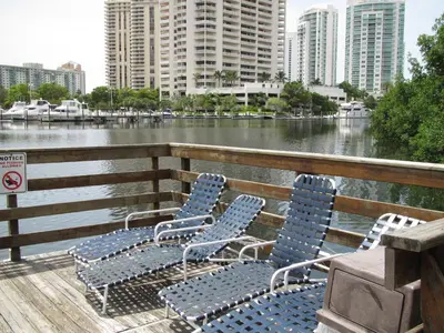 four blue chairs sitting on a deck next to the water at Resort Style In Aventura Florida in Aventura