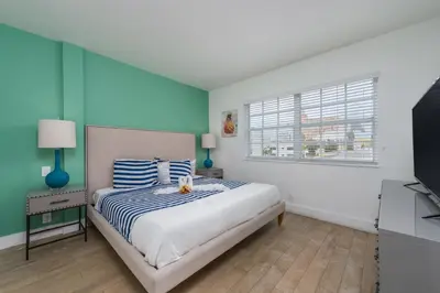 a bedroom with a large bed and a window at SoBe Lux Suites On Ocean in Miami Beach