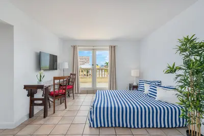 a bedroom with a bed and a desk and a television at SoBe Lux Suites On Ocean in Miami Beach