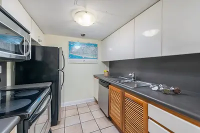 a kitchen with white cabinets and a black counter top at SoBe Lux Suites On Ocean in Miami Beach