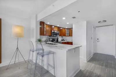 a white kitchen with a counter and stools in it at StayCozy Apartments at The Grand in Miami