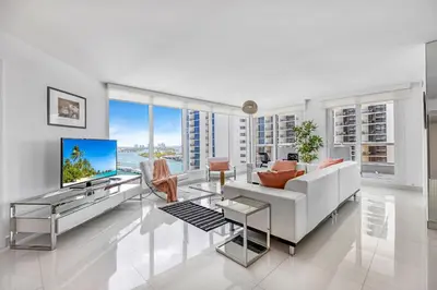 a living room with a white couch and a tv at StayCozy Apartments at The Grand in Miami