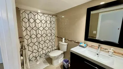 a bathroom with a toilet and a sink and a mirror at Sunny Isles Condo Resort in Miami Beach