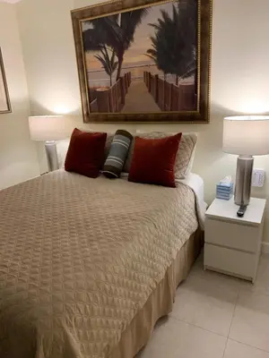 a bedroom with a bed with red pillows and a painting on the wall at Fantasy Island Inn, Caters to Men in Fort Lauderdale