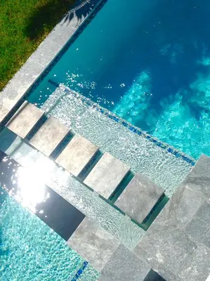 a swimming pool with blue water and the sun in the water at CASA HERMÈS Wilton Manor - Gay Guesthouse in Fort Lauderdale