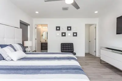 a white bedroom with a bed and a television at CASA HERMÈS Wilton Manor - Gay Guesthouse in Fort Lauderdale