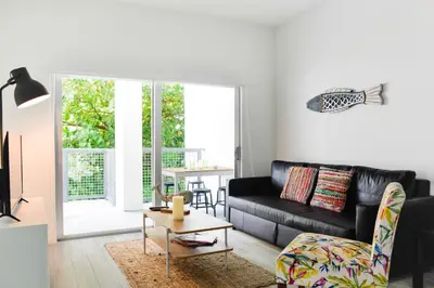 a living room with a black couch and a table at Amazing 2 BR Condo At Wynwood With Parking in Miami
