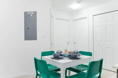 a dining room with a white table and green chairs at Amazing 2 BR Condo At Wynwood With Parking in Miami