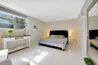 a white bedroom with a bed and a window at The Tides Apartments on the beach in Hollywood