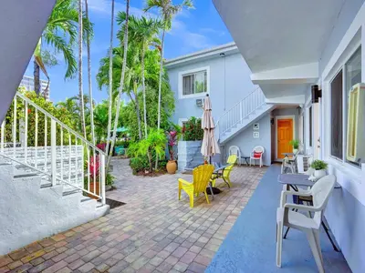 a patio with yellow chairs and tables and a white house at Beach Tide Motel in Hollywood