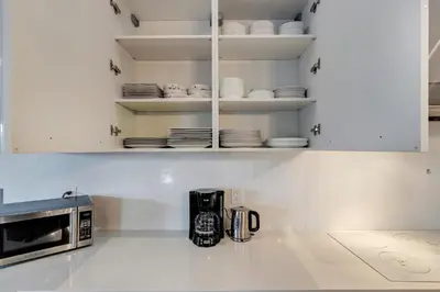 a kitchen with white cabinets and a microwave at Modern villa w lake view heated pool grill in Hollywood