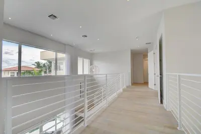 a hallway of a house with white walls and windows at Modern villa w lake view heated pool grill in Hollywood