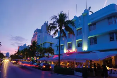 a city street with a building and palm trees at night at Heart of South Beach / Modern Apartment / Ocean Drive - Carlyle in Miami Beach
