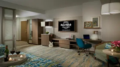 a hotel room with a desk and a living room at The Guitar Hotel at Seminole Hard Rock Hotel & Casino in Fort Lauderdale