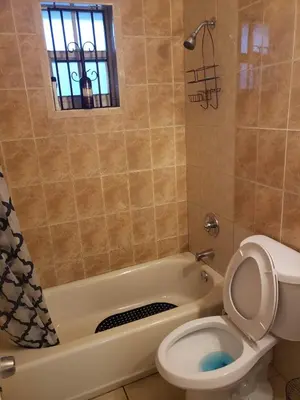 a bathroom with a toilet and a tub with a window at Miami Cheapest Place in Miami