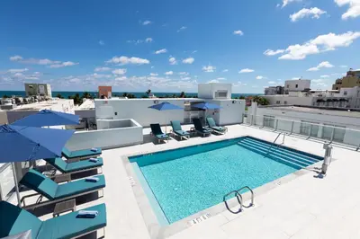 a pool on the roof of a building with chairs and umbrellas at Penguin Hotel in Miami Beach