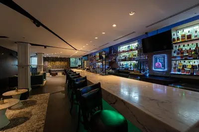 a bar with a long wooden counter and chairs at Albion Hotel in Miami Beach