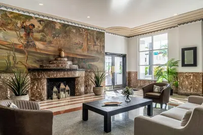 a living room with a fireplace and a painting on the wall at Essex House Hotel in Miami Beach