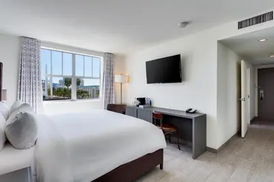 a hotel room with a bed and a desk and a television at Clinton Hotel South Beach in Miami Beach