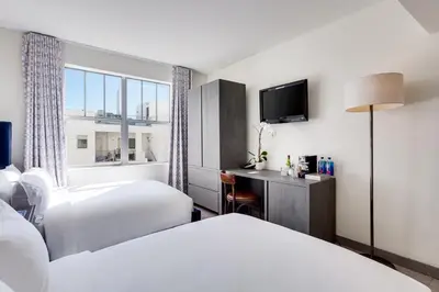 a hotel room with two beds and a television at Clinton Hotel South Beach in Miami Beach