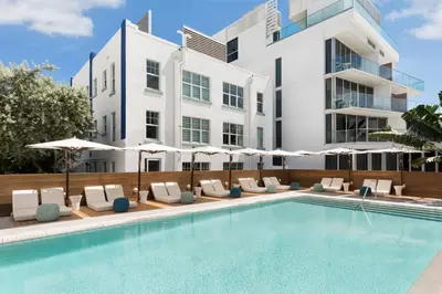 a pool with chairs and umbrellas in front of a building at Park Central South Beach in Miami Beach