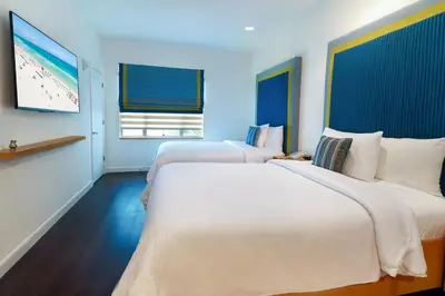 a hotel room with two beds and a television at The Tony Hotel South Beach in Miami Beach