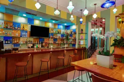 a bar in a restaurant with stools and a tv at The Tony Hotel South Beach in Miami Beach