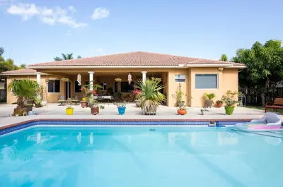 a house with a swimming pool in front of a house at Yuli's Home in Miami