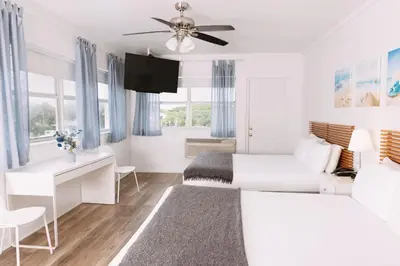 a white bedroom with a bed and a desk at Lorraine Hotel in Miami Beach