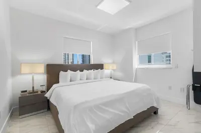a white bedroom with a large bed and a window at Fortune House Hotel Suites in Miami