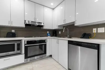 a kitchen with white cabinets and stainless steel appliances at Fortune House Hotel Suites in Miami