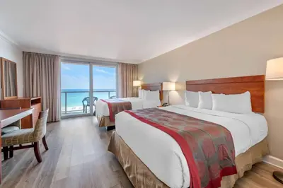 a hotel room with two beds and a desk at Ramada Plaza by Wyndham Marco Polo Beach Resort in Miami Beach