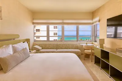 a bedroom with a bed and a living room with a view at The Shelborne by Proper, a Member of Design Hotels in Miami Beach