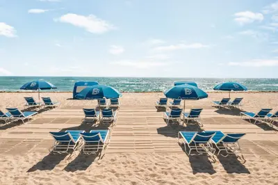 a group of chairs and umbrellas on a beach at Waldorf Towers South Beach in Miami Beach