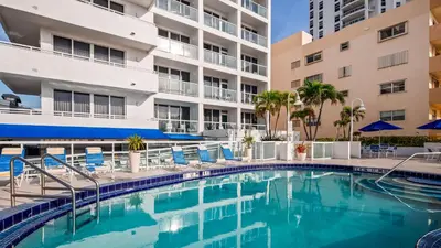 a swimming pool with chairs and a building at Best Western Plus Atlantic Beach Resort in Miami Beach