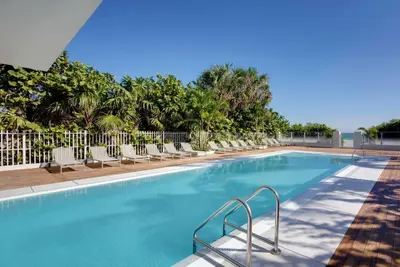 a swimming pool with lounge chairs and trees at MB Hotel, Trademark Collection by Wyndham in Miami Beach