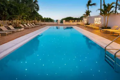 a large swimming pool with chairs and blue water at MB Hotel, Trademark Collection by Wyndham in Miami Beach