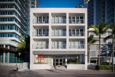 a white building with palm trees in front of it at MB Hotel, Trademark Collection by Wyndham in Miami Beach