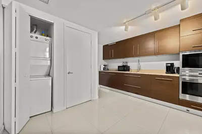 a kitchen with a white refrigerator and wooden cabinets at Luxury 1 BR Condo W Icon Brickell-Waterviews in Miami
