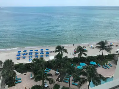 an aerial view of a beach with palm trees and blue umbrellas at Tides Beachfront Resort - 2 Bedroom Direct Oceanview Condo in Hollywood