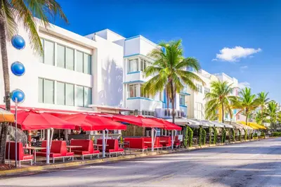 a street with red chairs and umbrellas in front of a building at Sobe Apartments in Miami Beach