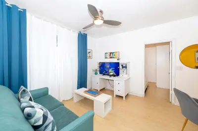 a living room with a blue couch and a tv at Sobe Apartments in Miami Beach