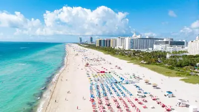 a beach with chairs and umbrellas and the ocean at Sofi Beach Apartments in Miami Beach