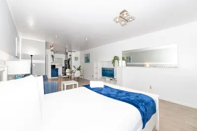 a white bedroom with a large bed and a living room at Sofi Beach Apartments in Miami Beach