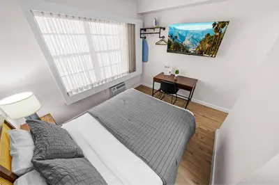 a bedroom with a bed and a desk and a window at Greenview Hotel By Lowkl in Miami Beach