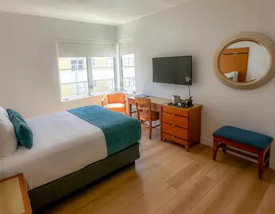 a bedroom with a bed and a desk and a television at Avalon Hotel in Miami Beach