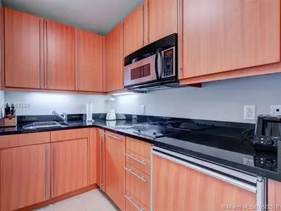 a kitchen with wooden cabinets and a microwave at Private condo hotel at Four Seasons Brickell in Miami