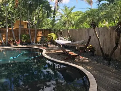 a pool with a hammock and a chair next to a fence at Little havana paradise in Miami